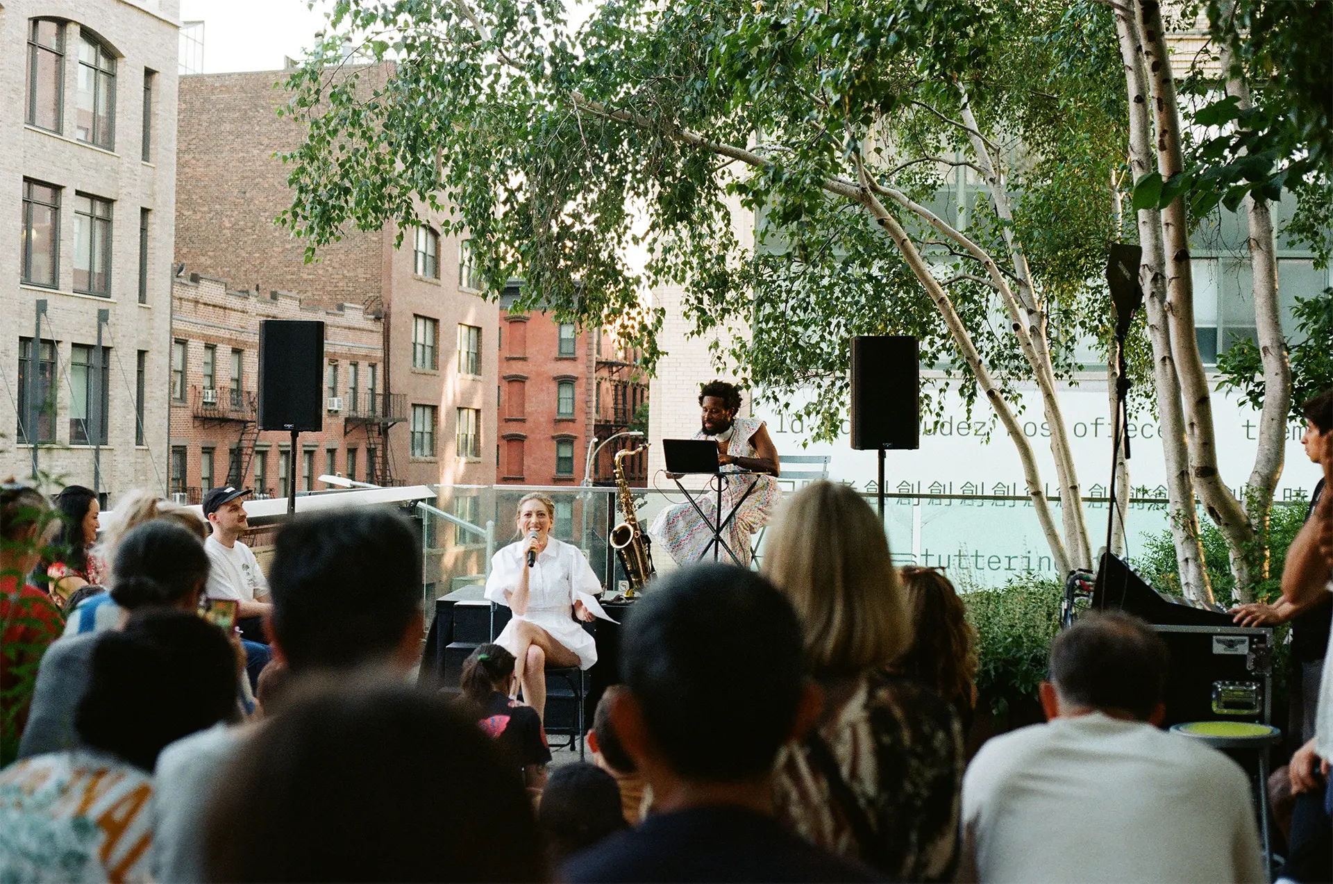 A woman dressed in white sits in a chair on the stage.