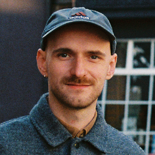 A portrait of Conor Foran smiling at the camera and wearing a cap.
